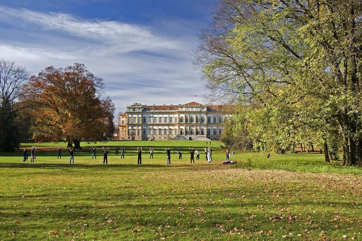 Ein Park mit einem Gebäude im Hintergrund, Bäumen und Personen.