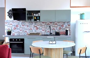 Cozinha moderna com mesa de jantar redonda, forno embutido e geladeira.