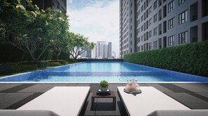 A modern outdoor swimming pool with lounge chairs and a potted plant, surrounded by high-rise buildings. - Room-regent Home Bang Na Condo- Private (Bangkok)
