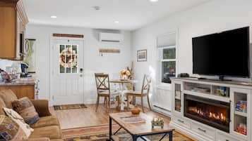 A living room with a fireplace, a television, and a dining area with chairs and a table.