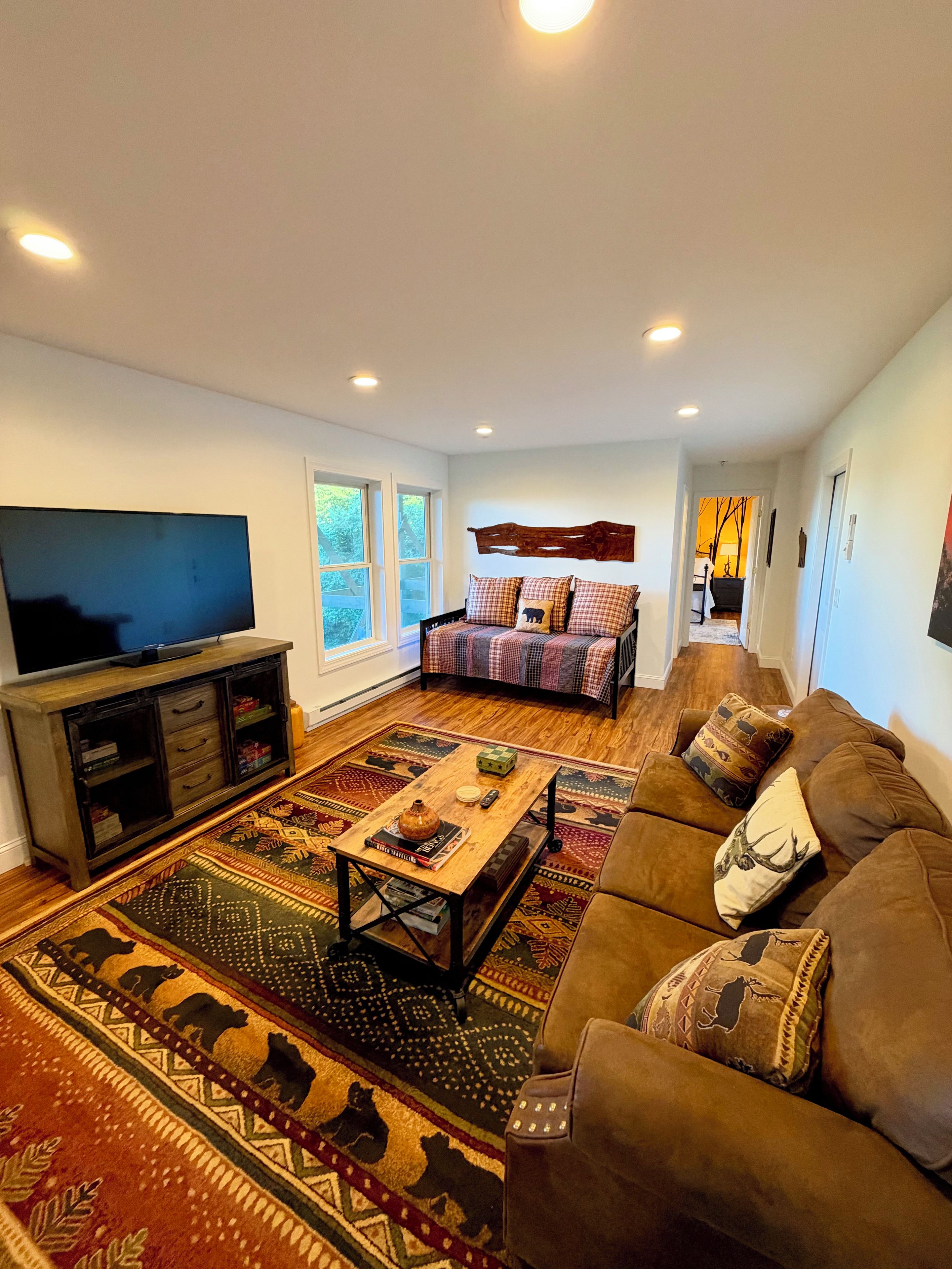 A living room with a television, sofa, coffee table, and patterned rugs.
