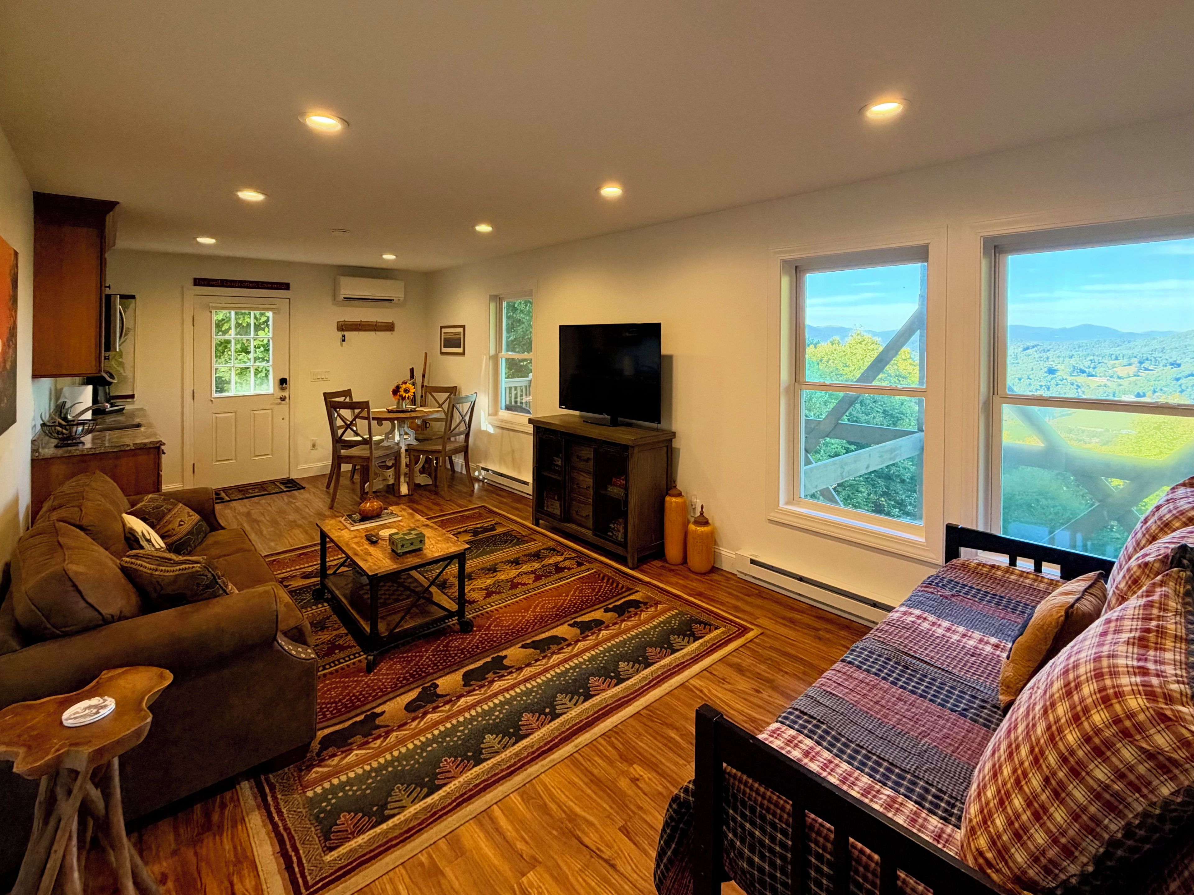 A living room with a sofa, a coffee table, a TV, and a large window with a view.