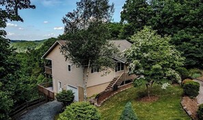 A two-story house with a front deck and a staircase leading to the entrance. - Serene Sunrise Long Range Mountain View 1-bedroom home in charming Blowing Rock (Blowing Rock)