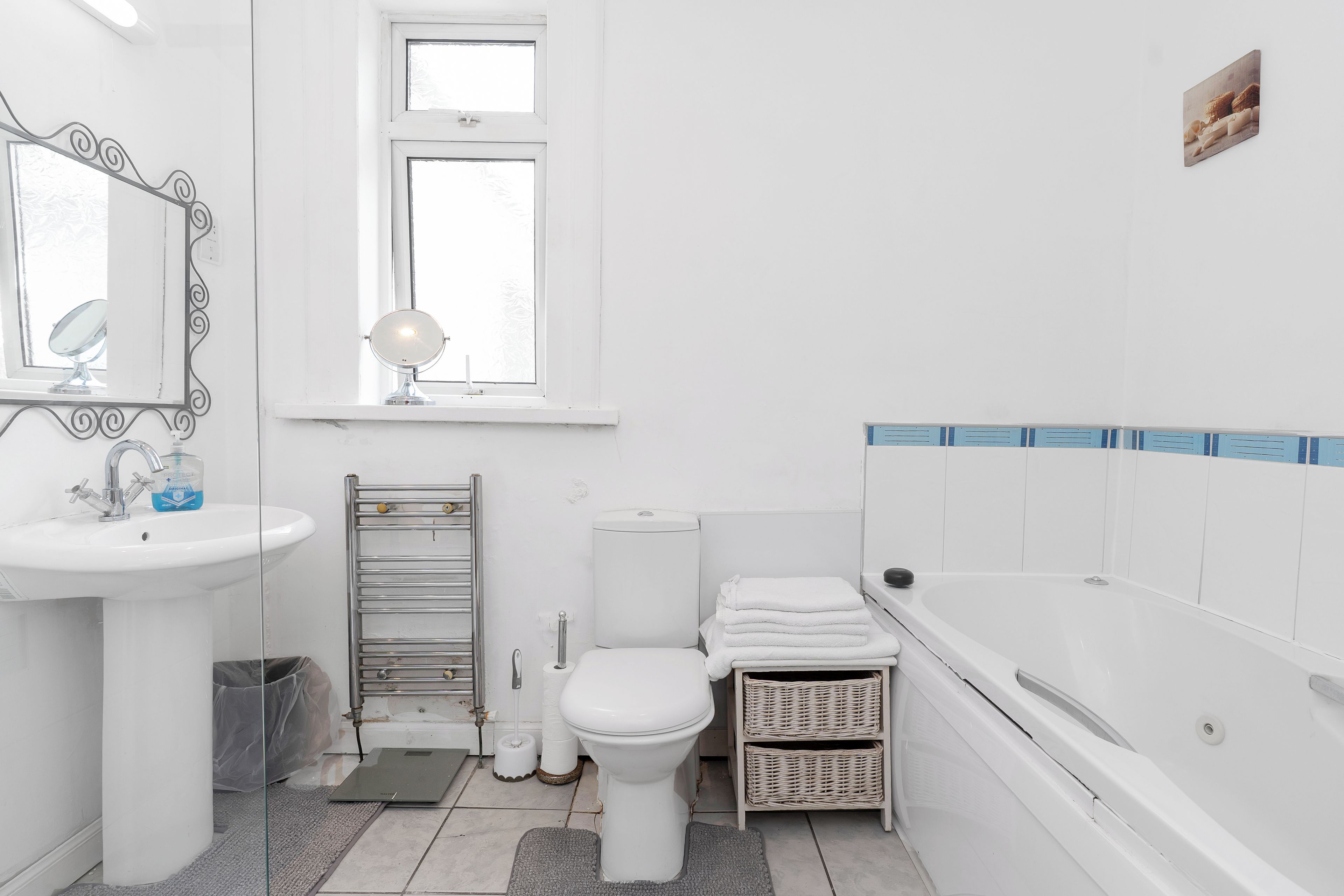 A bathroom with a sink, mirror, toilet, and bathtub.
