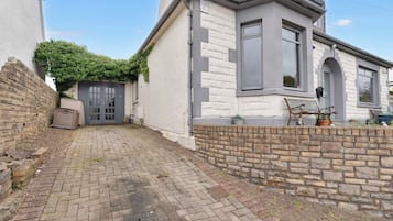 A residential property with a paved driveway, a brick wall, and a window with shutters.