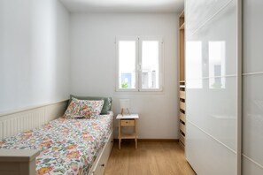 Une petite chambre à coucher avec un lit, une table de chevet, une fenêtre et une armoire.