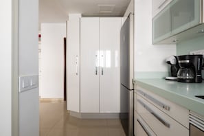 Une cuisine moderne avec des meubles blancs, une machine à café et un réfrigérateur.