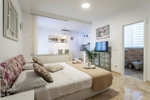 Quarto de hotel com cama, sofá, televisão, banheiro e vista para a cidade.