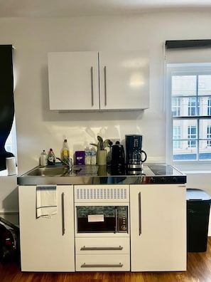 A compact kitchenette with a microwave, oven, and coffee maker. - Apartment Sleeps 2 With Wifi (London)