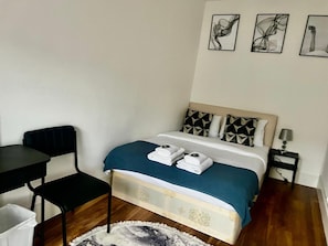 A small, neatly arranged bedroom with a bed, a chair, a bedside table, and a lamp. - Apartment Sleeps 2 With Wifi (London)