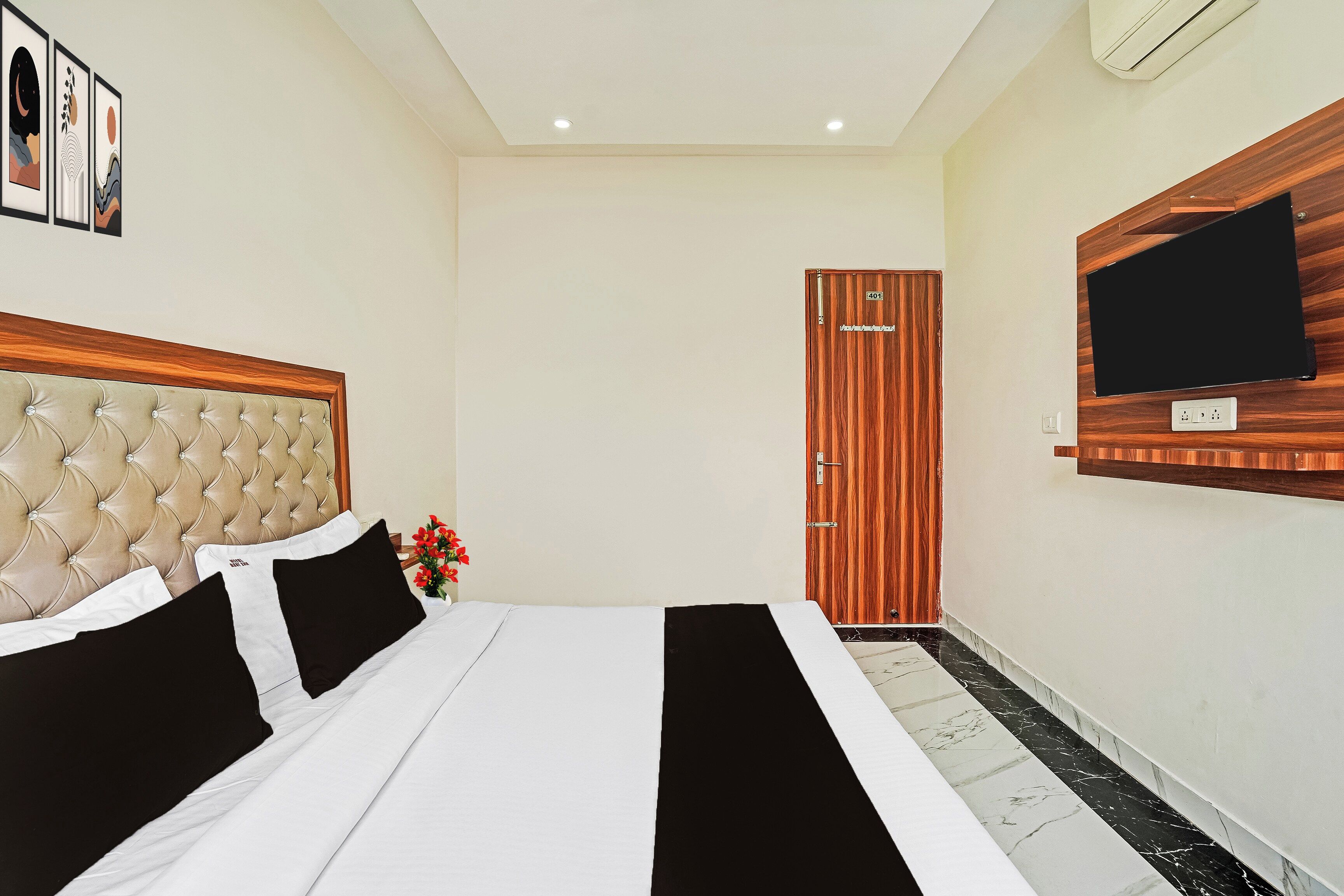 A hotel room with a bed, a television mounted on the wall, and a door.
