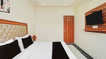 A hotel room with a bed, a television mounted on the wall, and a door.