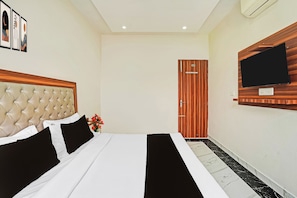 Una habitación de hotel con una cama, un televisor en la pared y una puerta.