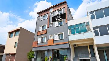 Un edificio de varios pisos con fachada moderna, que cuenta con un llamativo letrero 'BD' en la planta baja, un cartel de 'Collection' sobre la entrada y una escalera que conduce a la entrada principal.