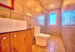 Un baño con inodoro blanco, mueble de madera y paredes con azulejos.