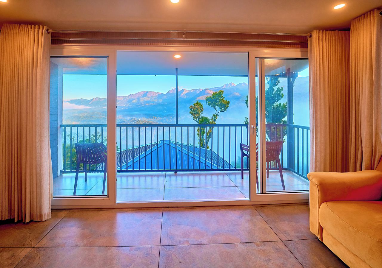 A room with a large sliding glass door leading to a balcony with a view of mountains.