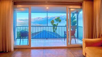 A room with a large sliding glass door leading to a balcony with a view of mountains.