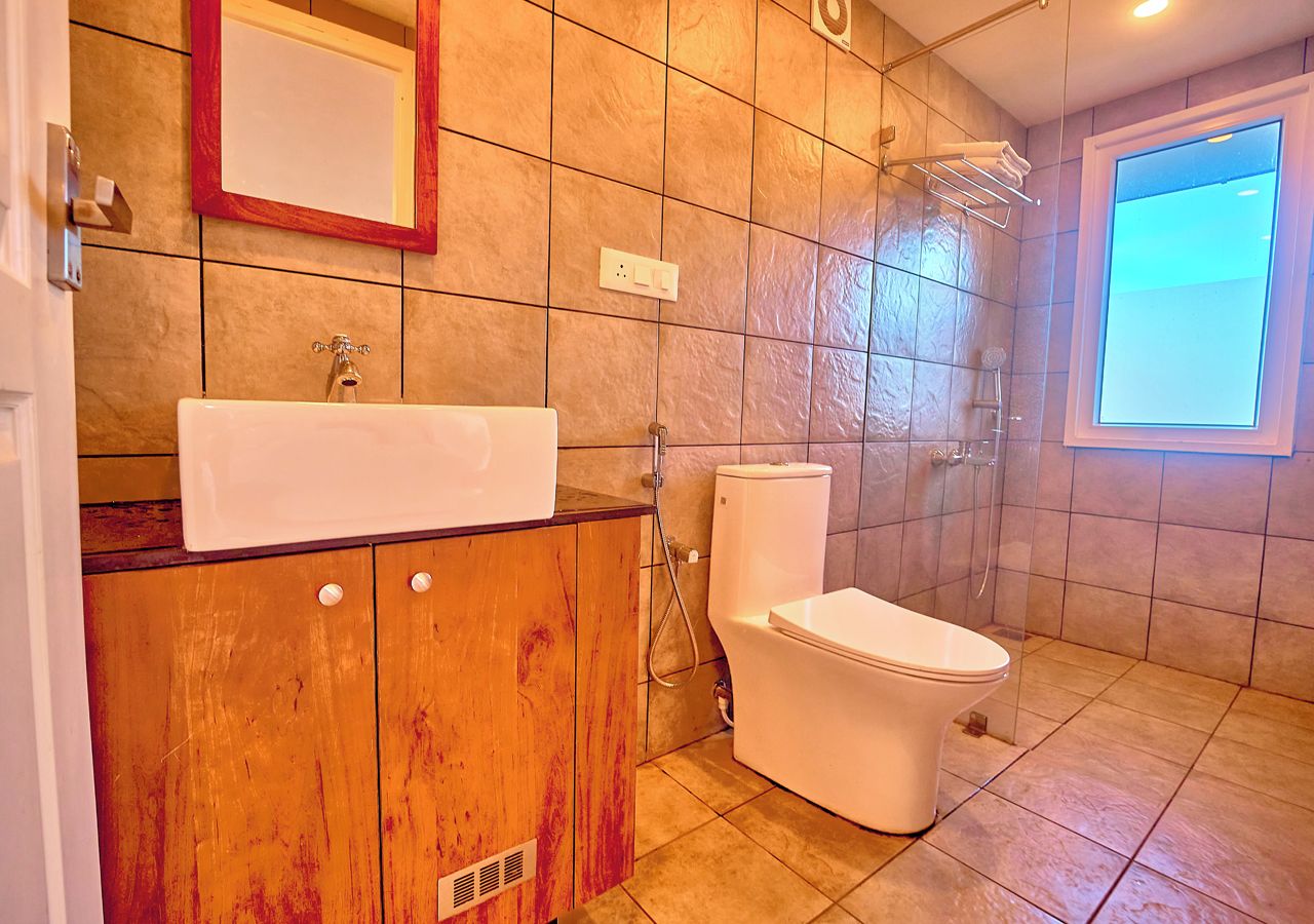 Ein Badezimmer mit einem Holz-Waschtisch, einem weißen Waschbecken, einer Toilette und einer Duschkabine.