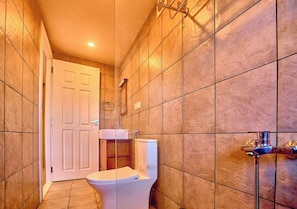 A bathroom with a toilet, a shower, and a sink.