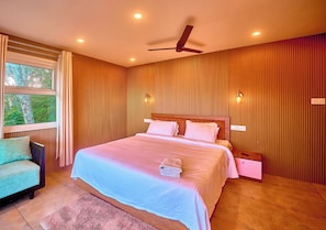 Un dormitorio con cama, mesita de noche, silla, ventilador de techo y ventana con cortinas.