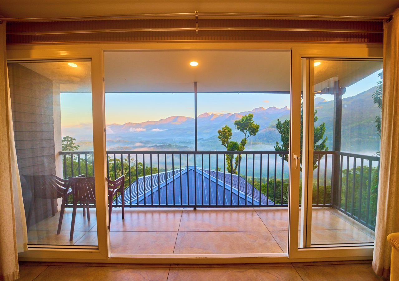 Ein Zimmer mit einer großen Schiebeglasdoor, die auf einen Balkon mit Bergblick führt.
