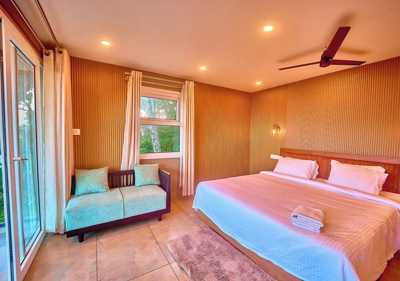 Une chambre à coucher avec un lit, un canapé, un ventilateur de plafond et une fenêtre avec des rideaux.