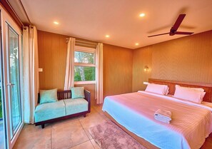 Un dormitorio con cama, sofá, ventilador de techo y ventana con cortinas.