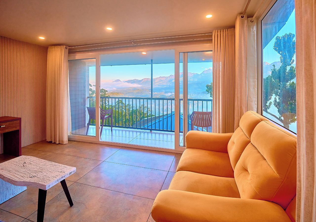 A living room with a sofa, a table, and a view of mountains through a glass door.