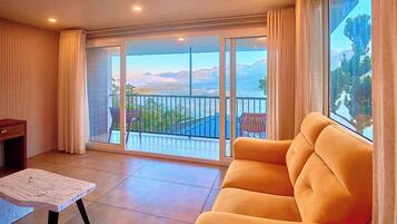 A living room with a sofa, a table, and a view of mountains through a glass door.