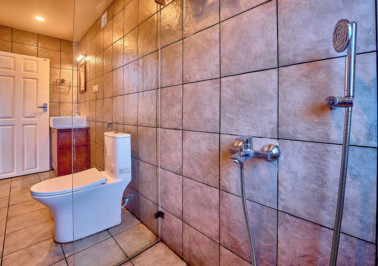 Ein Badezimmer mit Toilette, Dusche und gefliesten Wänden.