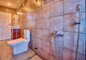 Un baño con inodoro, ducha y paredes de azulejos.