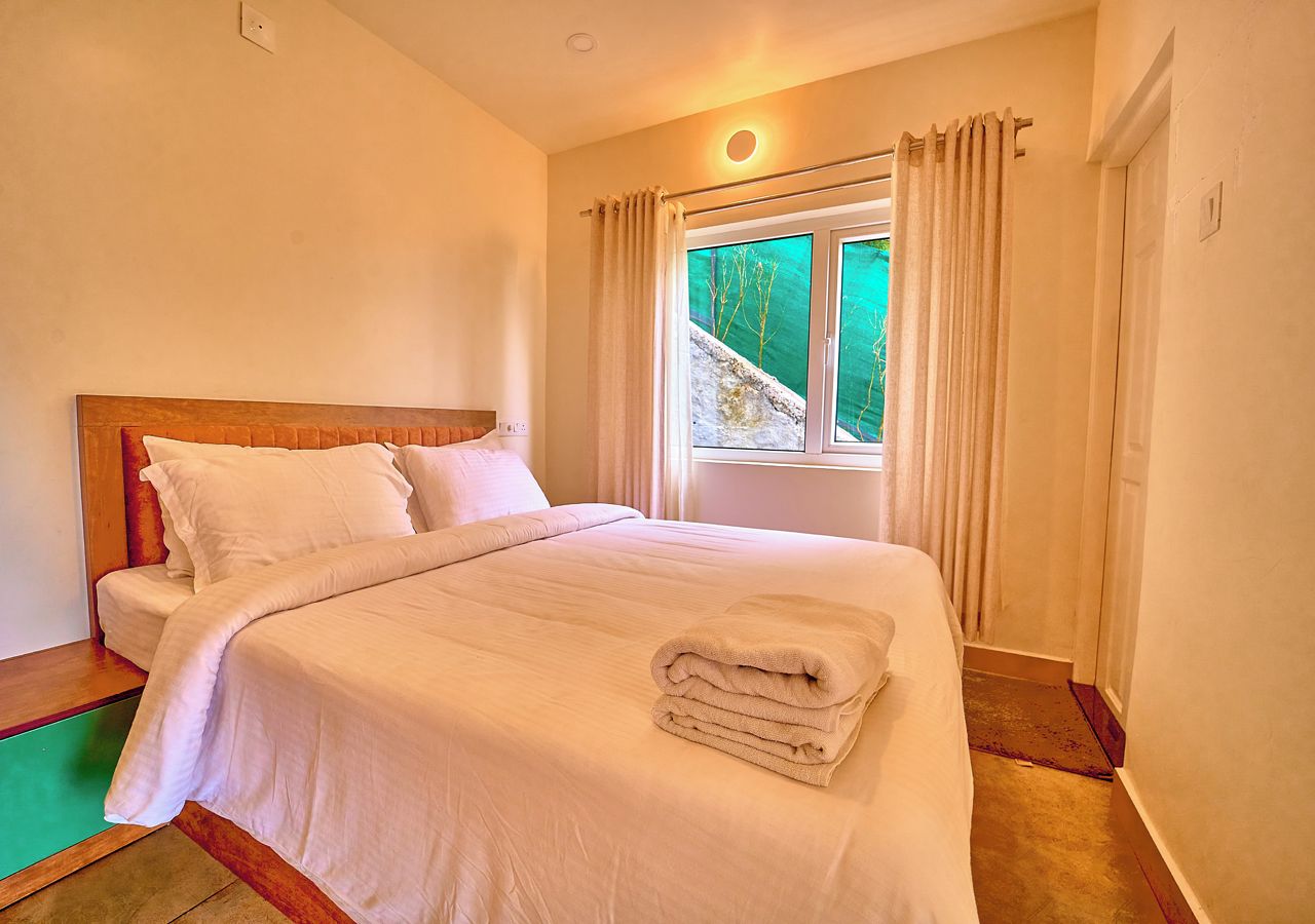 Une chambre d’hôtel avec un lit, des rideaux et une fenêtre donnant sur un paysage verdoyant.