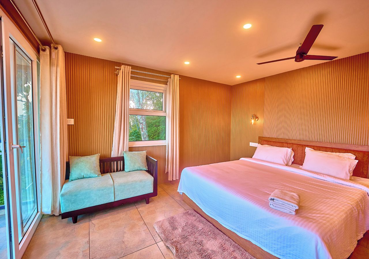 A bedroom with a bed, a sofa, a ceiling fan, and a window with curtains.