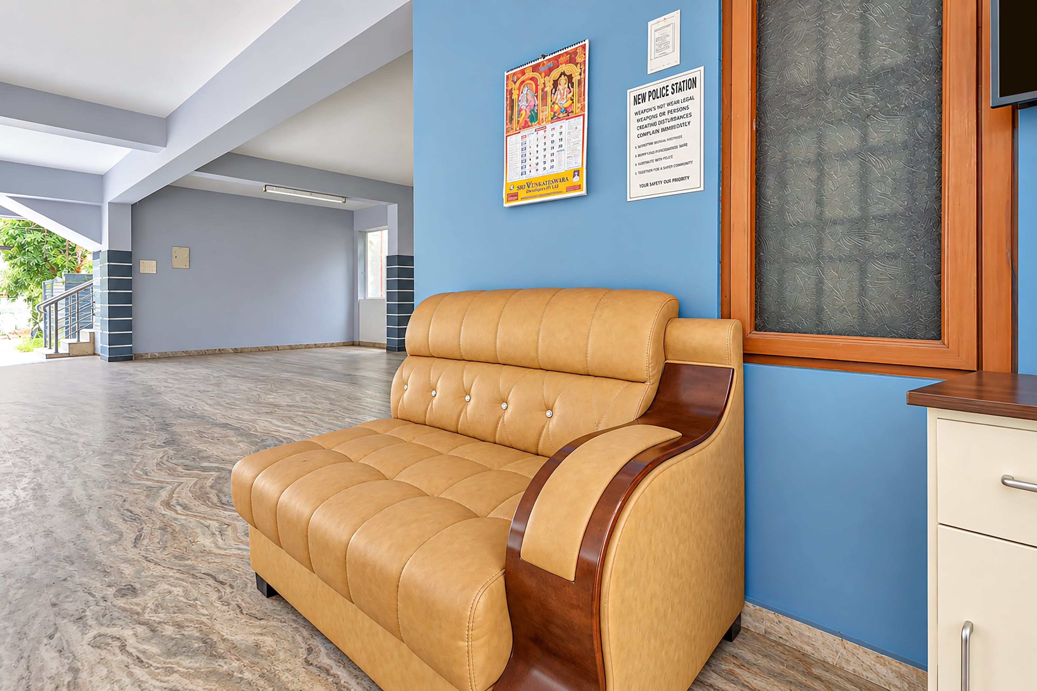 A reception area with a leather sofa, a wooden cabinet, and a wall with informational posters.