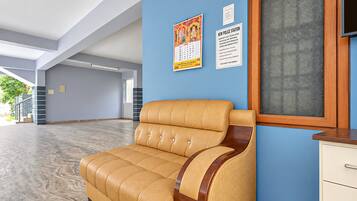 A reception area with a leather sofa, a wooden cabinet, and a wall with informational posters.