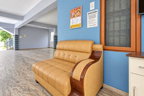 Una zona de recepción con un sofá de cuero, un armario de madera y una pared con carteles informativos.