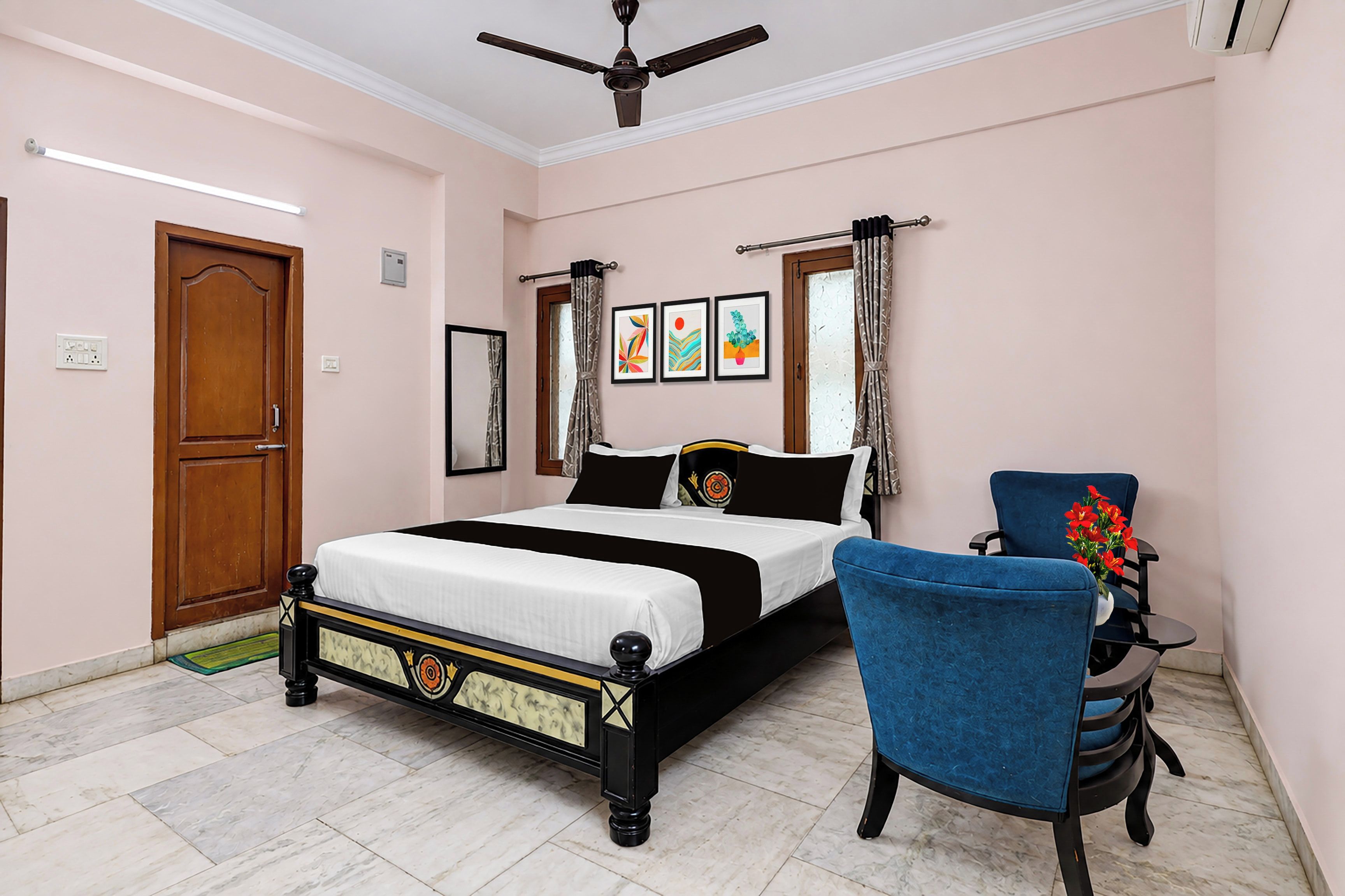 A bedroom with a bed, a chair, a ceiling fan, and artwork on the wall.