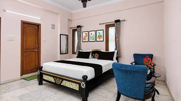 A bedroom with a bed, a chair, a ceiling fan, and artwork on the wall.