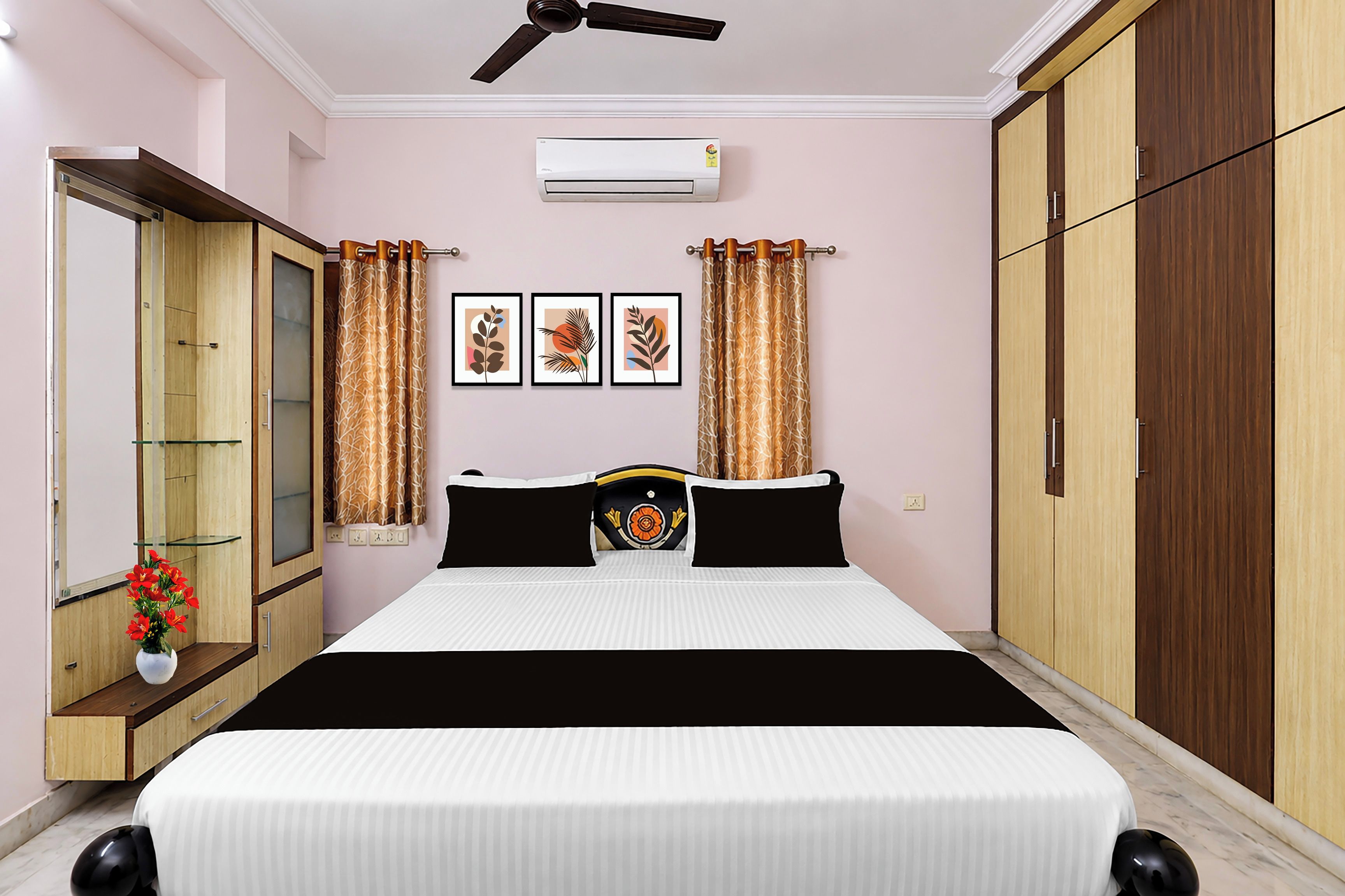 A bedroom with a bed, a ceiling fan, an air conditioning unit, a wardrobe, a mirror, and a window with curtains.