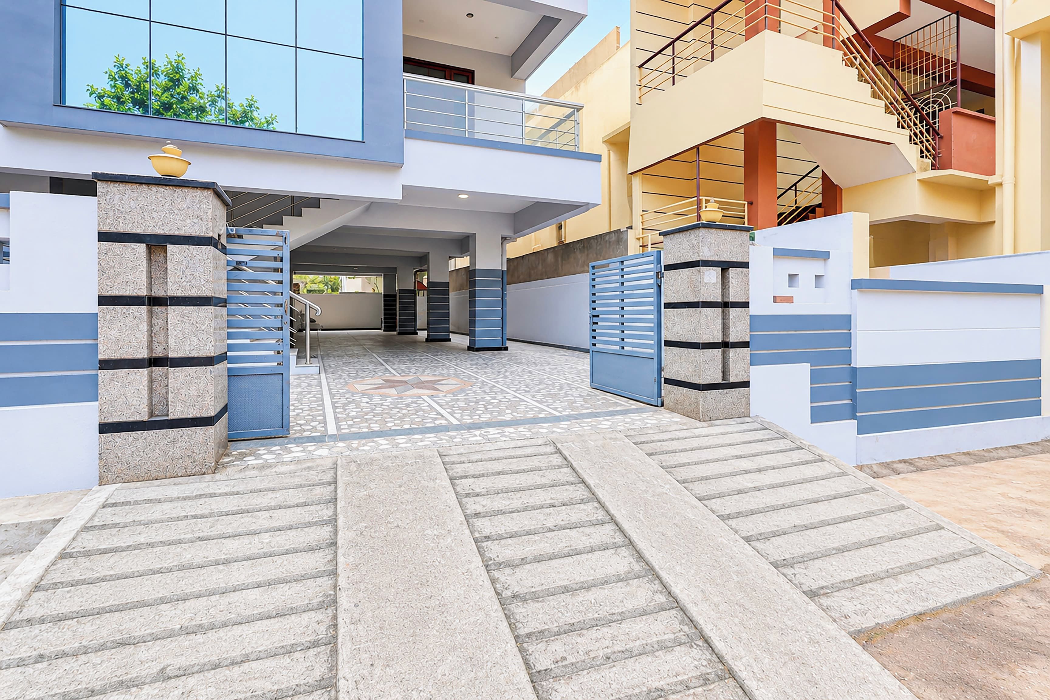 A modern residential entrance with a gated driveway leading to a two-story house.