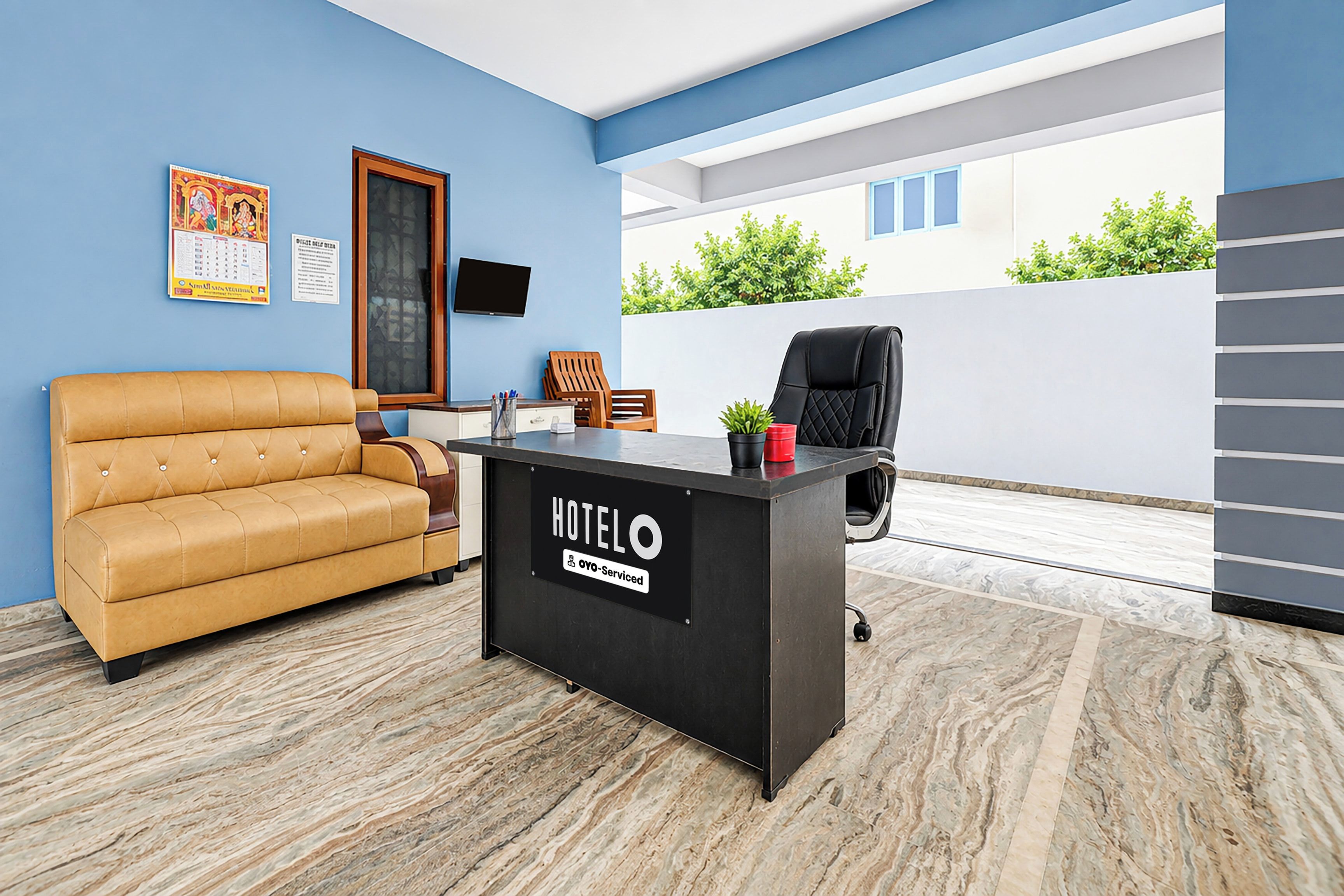 A hotel reception area with a sofa, a desk, and a chair.