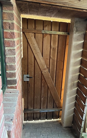 A wooden barn-style door with a metal latch, a brick wall, and a concrete foundation.