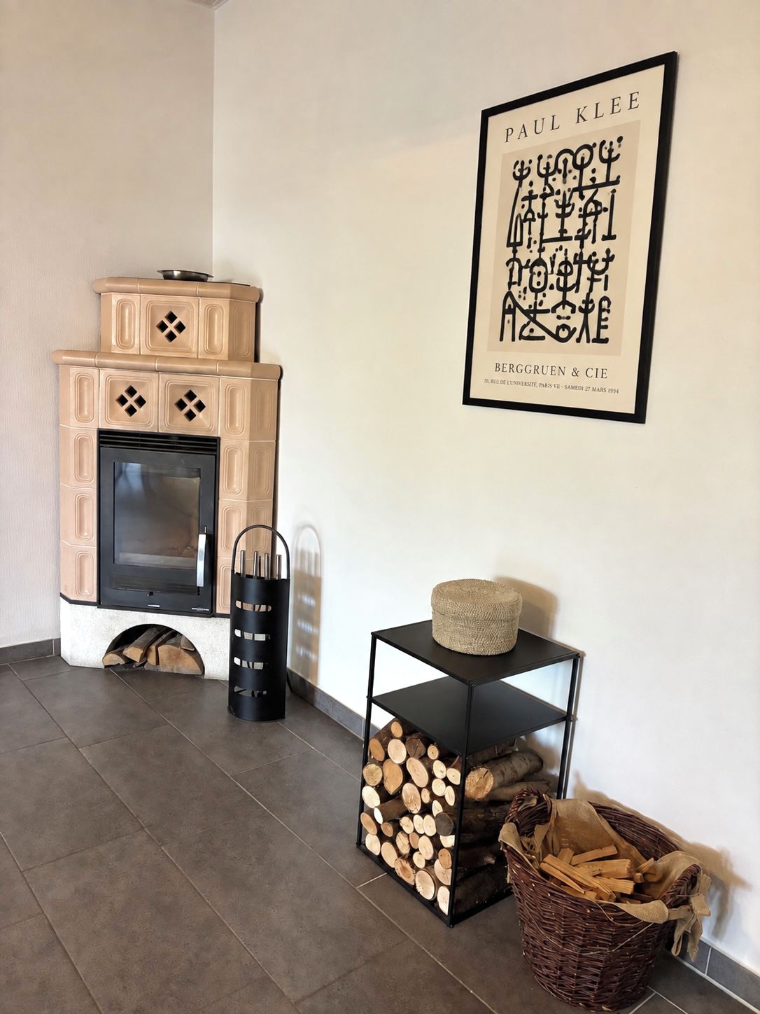 A modern living room with a fireplace, a framed artwork, and a stack of firewood.