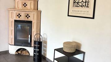 A modern living room with a fireplace, a framed artwork, and a stack of firewood.