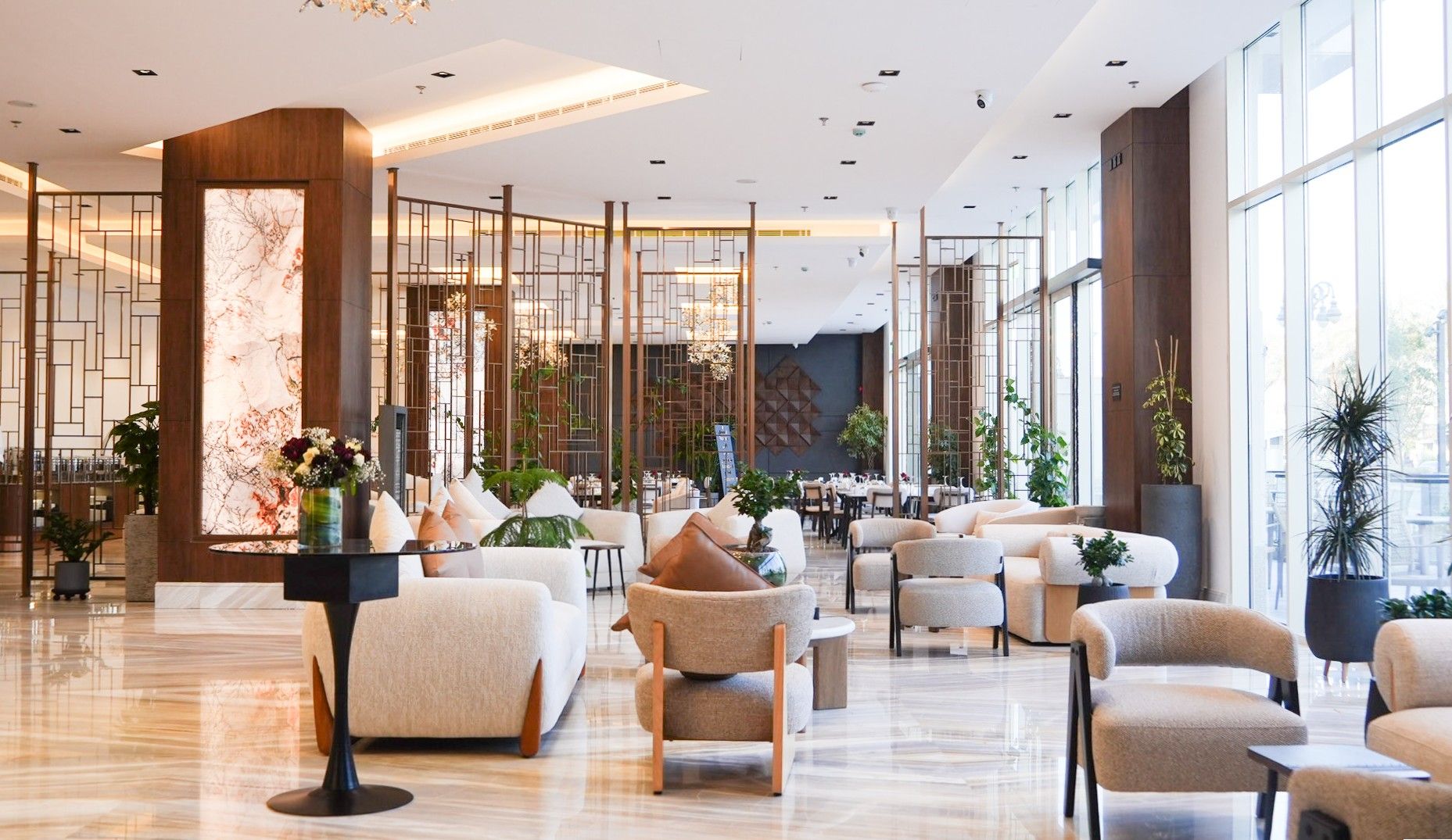 A spacious lobby with a modern design, featuring a reception desk, seating areas, and large windows allowing natural light.