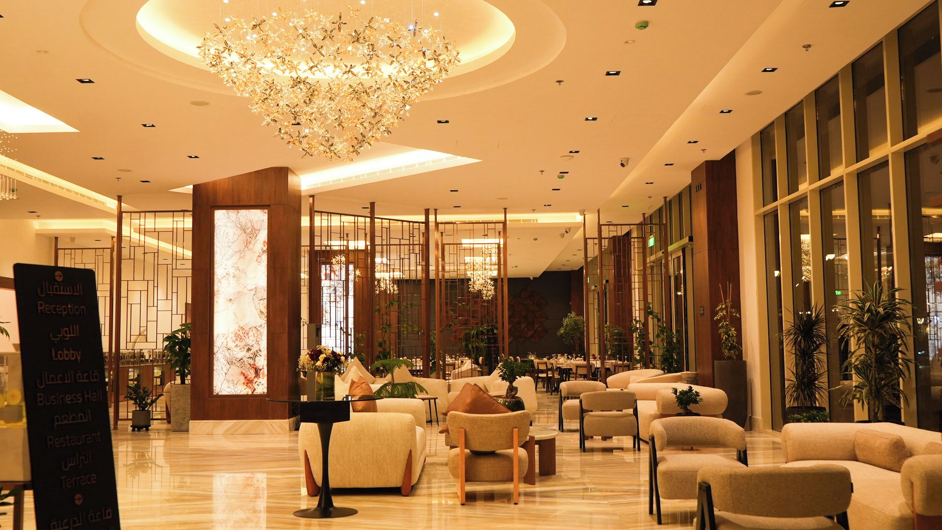 Un'ampia hall con un lampadario moderno, zone relax e una reception.