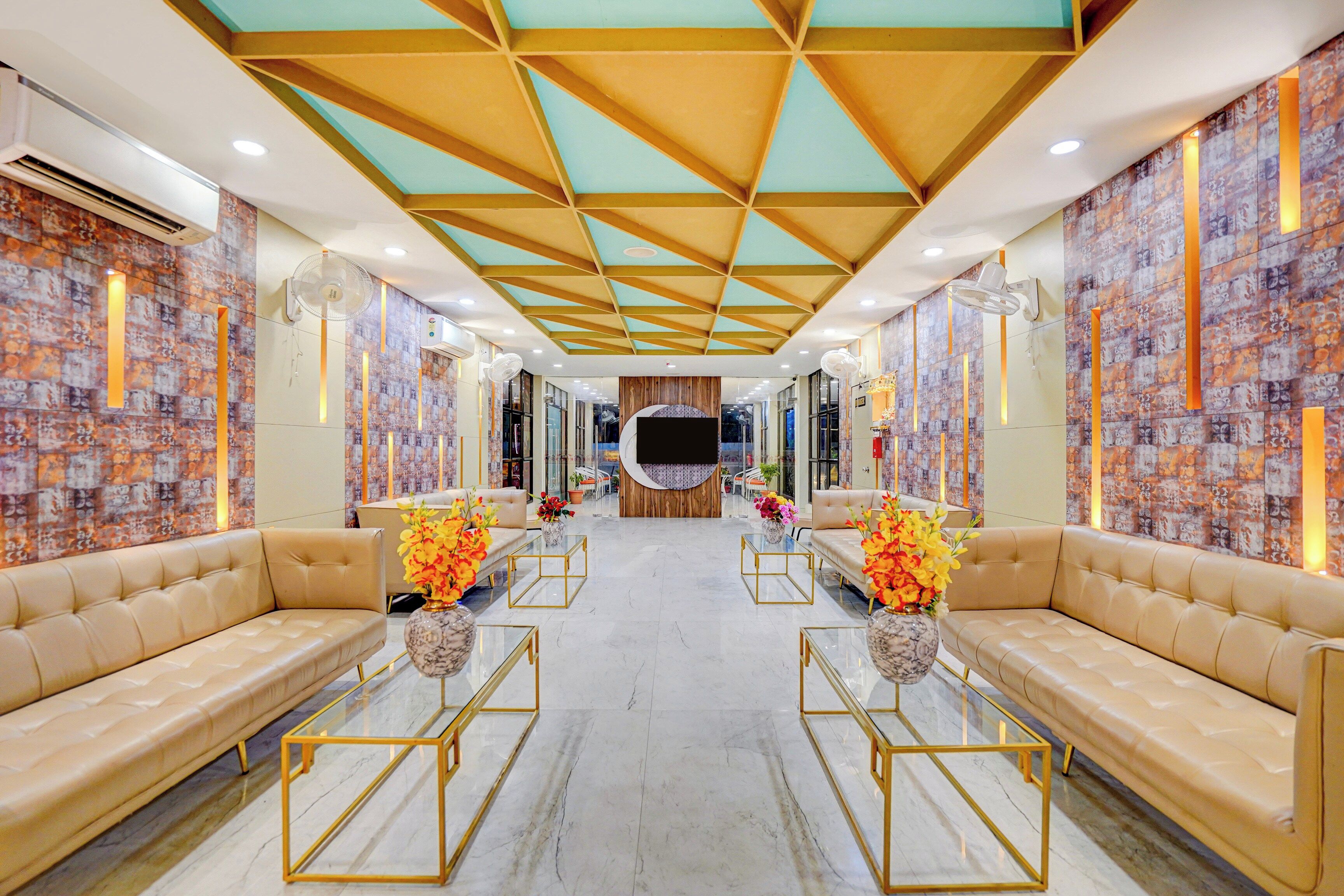 A hotel lobby with a modern design, featuring leather sofas, glass coffee tables, and a patterned wall.