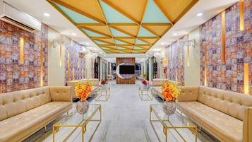 A hotel lobby with a modern design, featuring leather sofas, glass coffee tables, and a patterned wall.