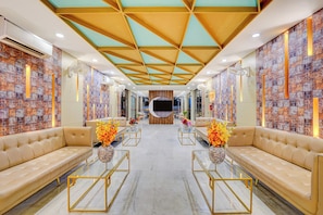 Un hall de hotel de diseño moderno, con sofás de cuero, mesas de centro de vidrio y una pared con estampado.