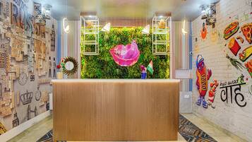 Una recepción con un fondo de pared verde, rodeada por una pared con nombres de varios países y un mural de alimentos.